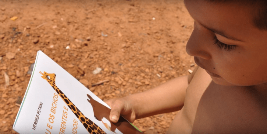 Garoto recebe livro do projeto Rallyteca | © Divulgação