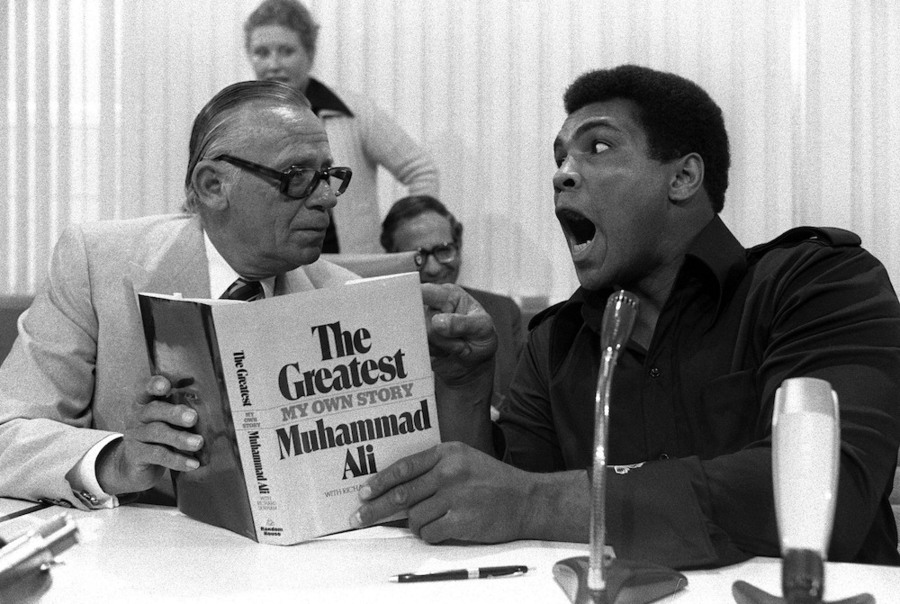 Willy Droemer, editor, à esquerda, da editora Droemer Knaur, junto com Muhammad Ali, campeão mundial de boxe, durante a apresentação conjunta da biografia de Ali na Feira do Livro de Frankfurt em 11 de outubro de 1975 | © picture-alliance / Sven Simon